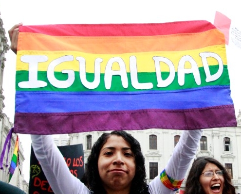 Imagen de una mujer con una bandera LGBTI en alto que dice "Igualdad"