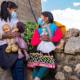 Imagen de dos niñas de la zona rural mirándose entre sí con muñecas en las manos